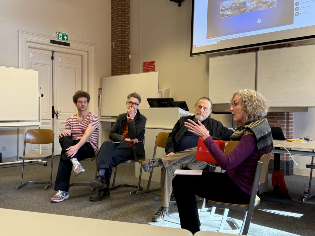 four conference participants sit facing the rest of the attendees while they speak on a panel